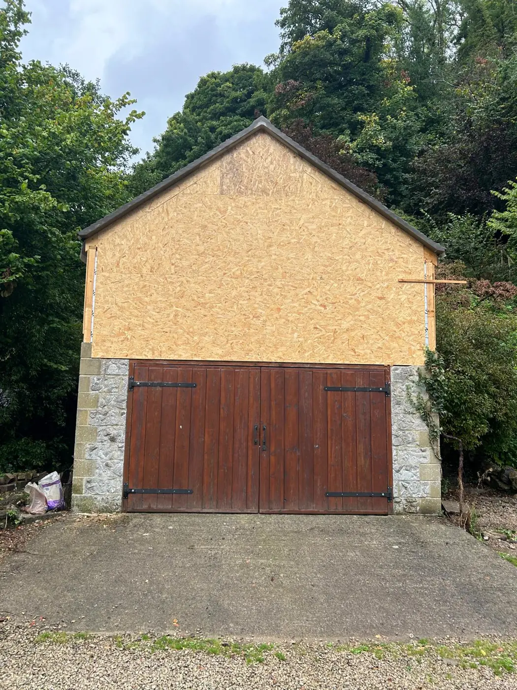 The same garage before: bare OSB board above stone walls