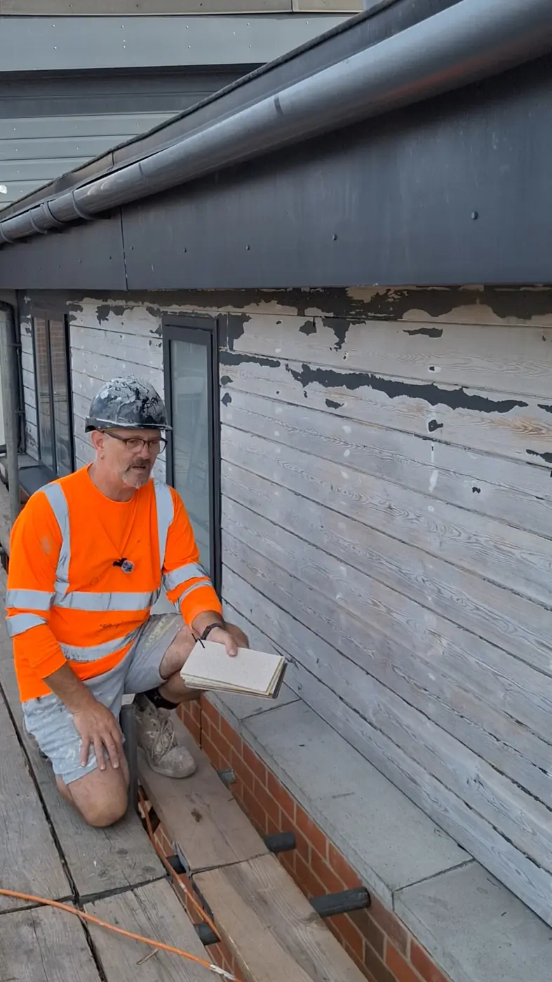 Mark on scaffold checking a wall and showing cork colour samples